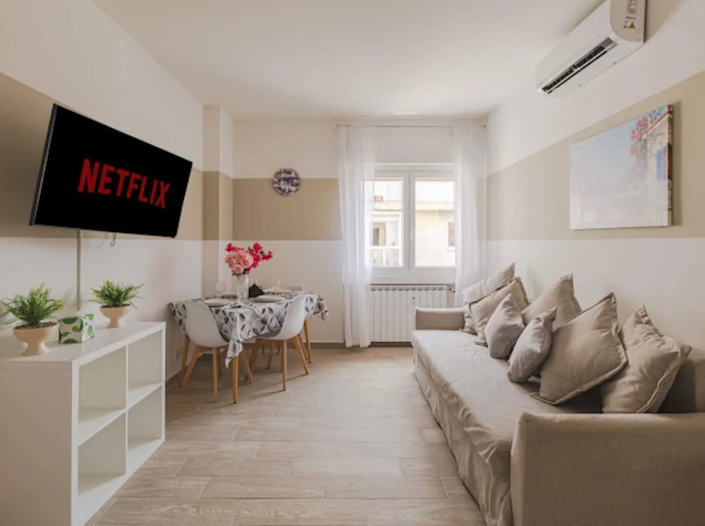 Soggiorno luminoso con divano, tavolo da pranzo e televisore